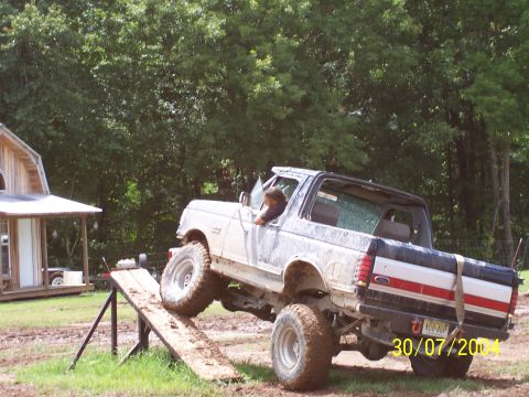 1979 Ford F-150 - A lifted pickup truck navigates a muddy obstacle course on a wooden ramp.