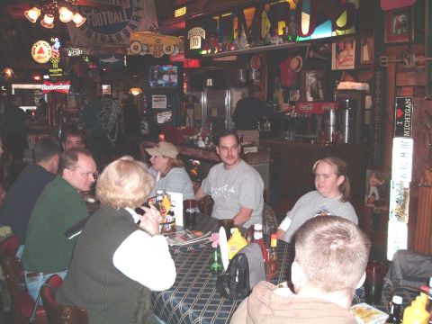 1984 Ford Bronco - A group of people are seated at tables inside a bar decorated with sports memorabilia.