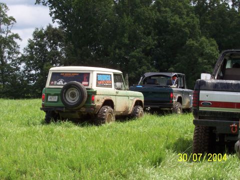 1979 Ford F-150 - Three off-road vehicles, including a green Ford Bronco, are parked in a field on a cloudy day.