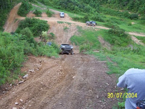 1979 Ford F-150 - Multiple off-road vehicles navigate a challenging dirt track in a hilly, wooded area.