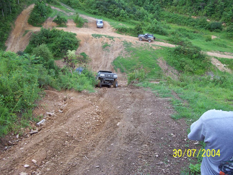 1979 Ford F-150 climbing a dirt hill, with two other ATVs visible on the track