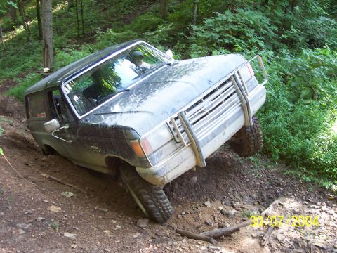 1979 Ford F-150 - A Ford Bronco navigates a challenging off-road trail, its tires digging into the mud.