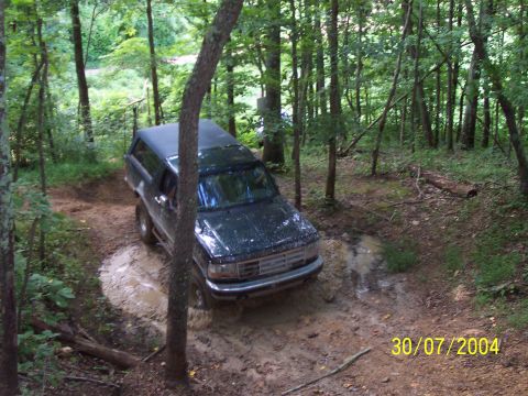 1979 Ford F-150 - Ford Bronco driving through mud on a wooded trail.