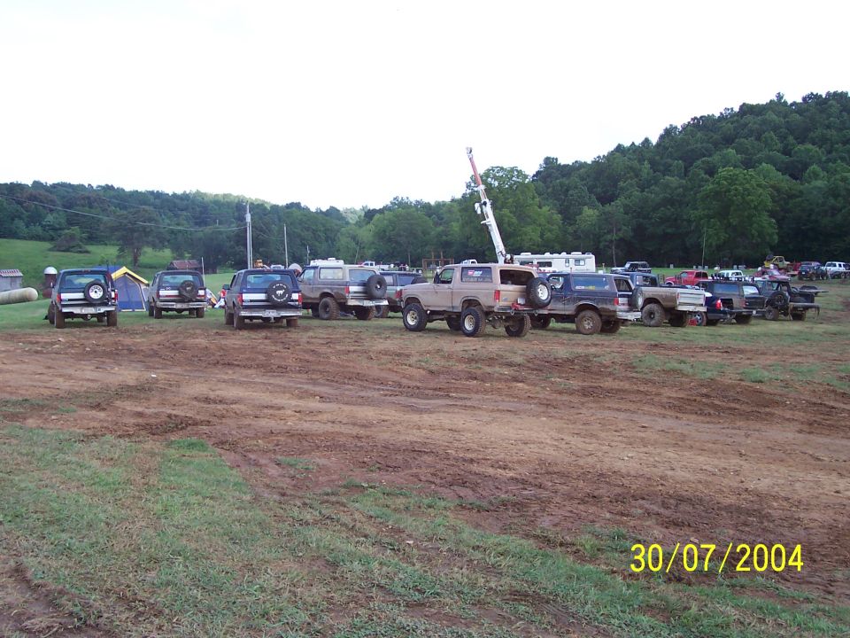 Tan Ford Bronco parked in a muddy field with other trucks