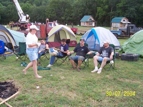 1979 Ford F-150 - A group of people are relaxing at a campsite with tents and various vehicles present.