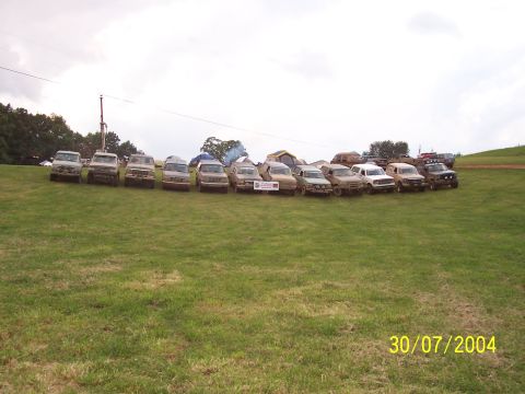 1979 Ford F-150 - A group of off-road vehicles are lined up on a field, with tents visible behind them.
