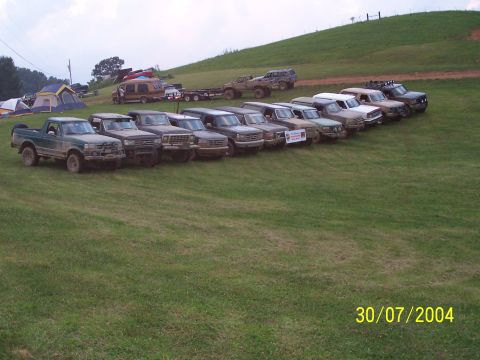 1979 Ford F-150 - A group of off-road vehicles are lined up on a grassy hillside on a cloudy day.