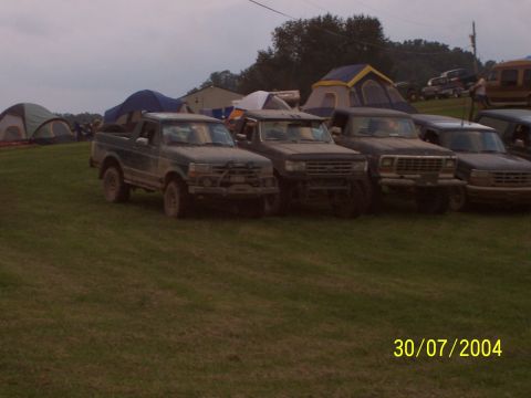 1979 Ford F-150 - Multiple trucks and tents are visible on a grassy field under an overcast sky.