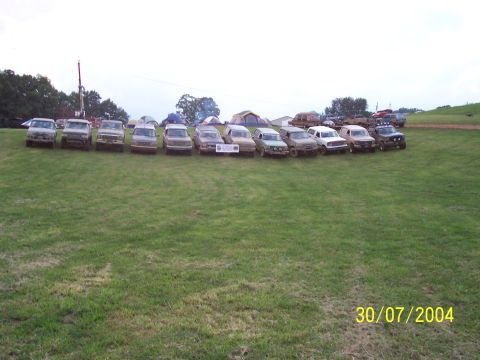 1979 Ford F-150 - Multiple trucks and SUVs are lined up on a grassy field, with tents visible in the background. The photo was taken on July 30, 2004.