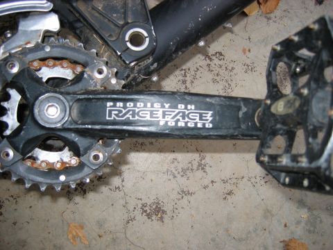 1995 Ford Bronco - Close-up of a bicycle's crankset and pedals, showing the 'Race Face Prodigy DH Forged' branding.