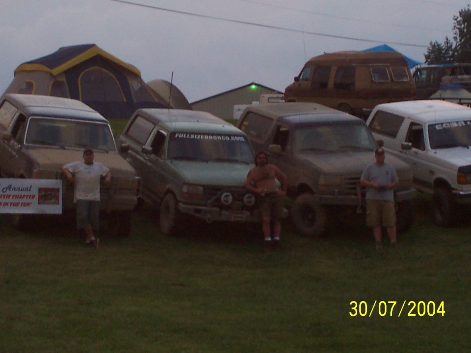 Tan 1992 Ford Bronco with a camper shell, parked on grass