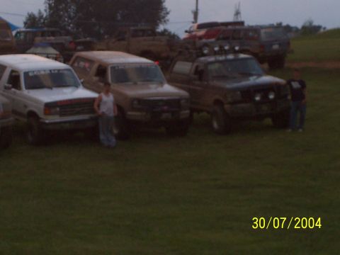 1979 Ford F-150 - Several trucks and SUVs are parked on a grassy field, with two individuals standing nearby.