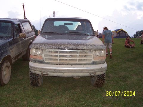 1979 Ford F-150 - A muddy Ford truck is parked on grass with tents and people in the background.