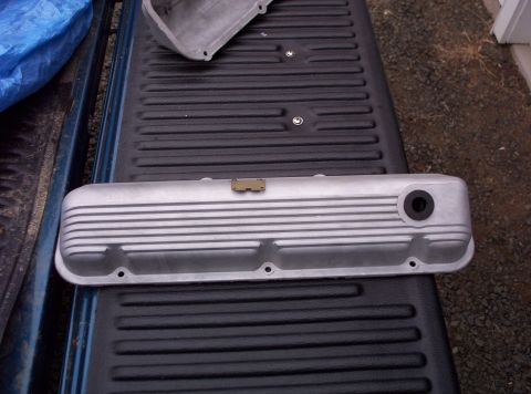 1991 Ford LTD Crown Victoria - An aluminum valve cover with horizontal fins and a brass clip is shown resting on a truck bed liner.