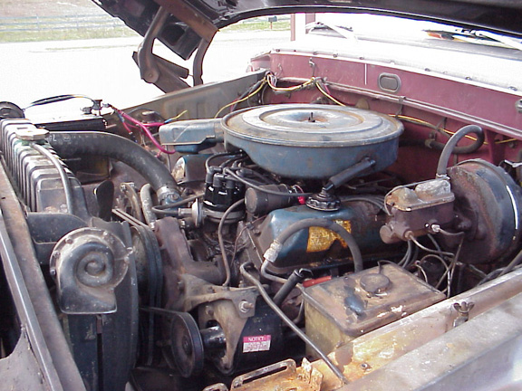 Engine bay with V8 engine, air cleaner, radiator, and brake booster visible. Some rust present