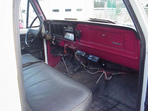 1973 Ford F-250 - The interior of a vintage Ford truck features a maroon dashboard and a dark gray bench seat.