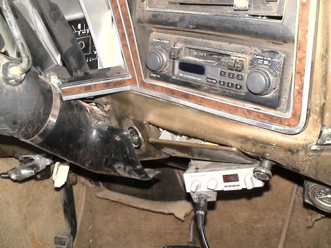 1979 Ford Bronco - Dusty interior close-up of a vintage truck dashboard with woodgrain trim, showing a Sony cassette head unit with rotary knobs and preset bu…