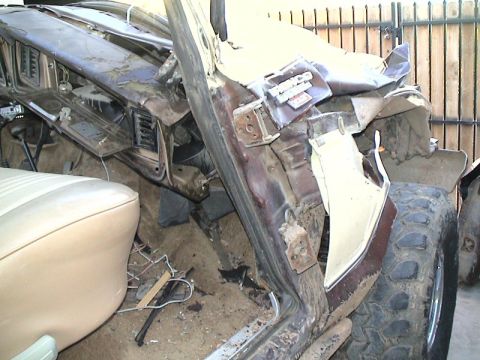 1979 Ford Bronco - Crushed and torn vehicle body showing a damaged A-pillar, dirt-covered dashboard and tan seat after a severe rollover or crash.