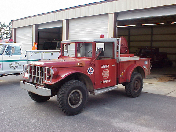 Red fire truck with 'ASBURY REHOBOTH' text, parked next to a white truck