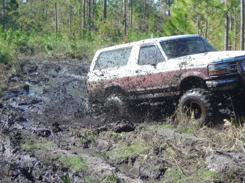 1993 Ford Bronco - Ford Bronco navigating a muddy trail in a wooded area.