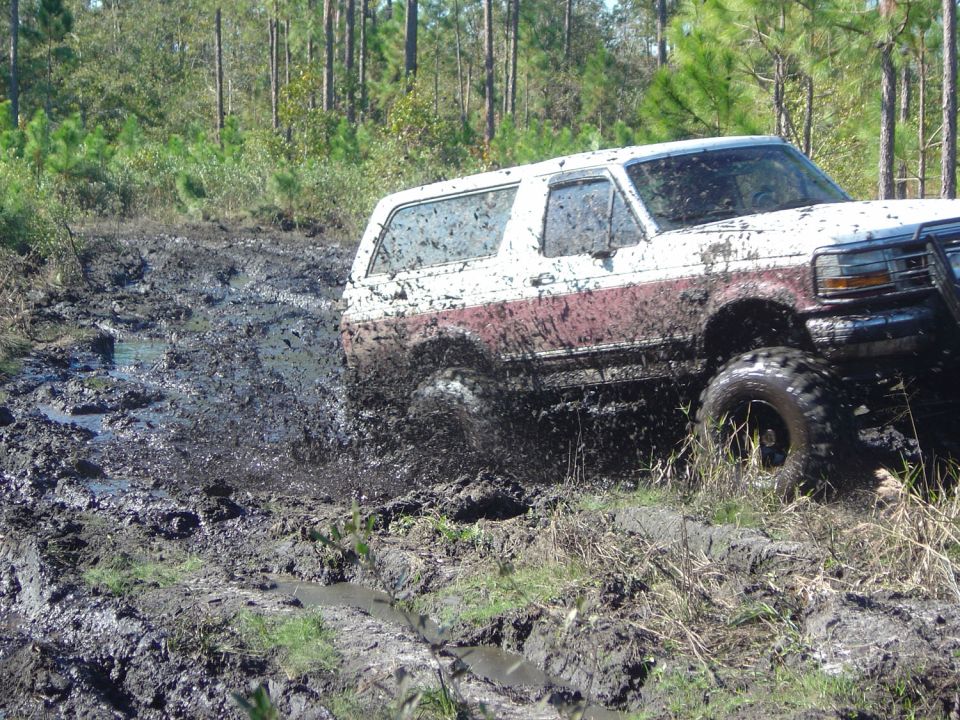1993 Ford Bronco splashing mud while off-roading