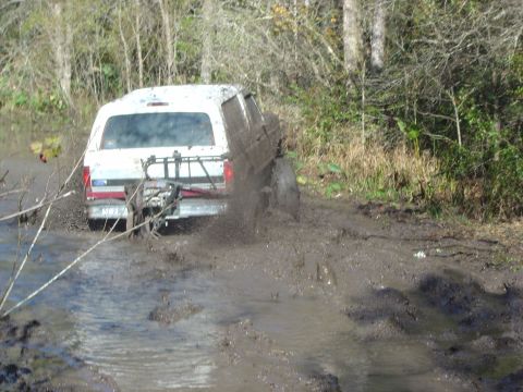 1993 Ford Bronco - Ford Bronco navigating a muddy trail, kicking up water and dirt.