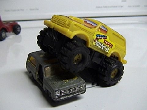1979 Ford Bronco - Two toy trucks are shown, one a yellow monster truck on top of a gray truck.