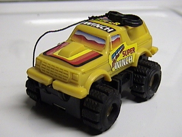 Yellow toy monster truck with "Super Winch" graphics and rainbow stripes on hood