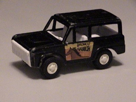 1979 Ford Bronco - A small black die-cast early-Bronco-style wagon toy photographed in three-quarter front view on a plain gray background. It has a white pai…