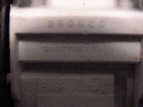 1979 Ford Bronco - Close-up of a vehicle part showing the 'Bronco' emblem and a VIN plate.