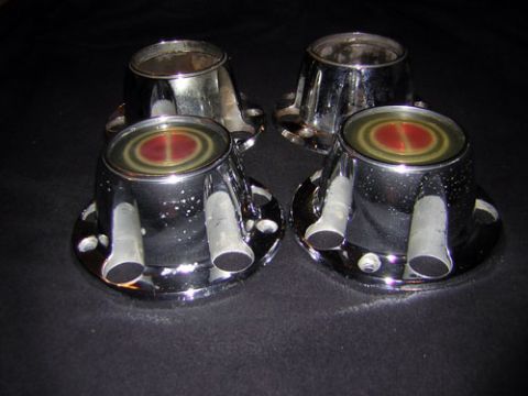 1995 Ford Bronco - A set of four chrome hubcaps with a red and yellow center emblem are displayed on a dark surface.
