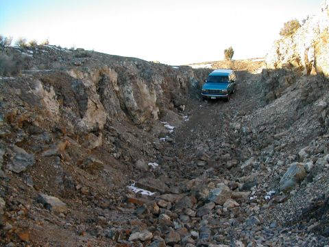1994 Ford Bronco - SUV navigates a rough, rocky terrain in a dry wash under a clear sky.