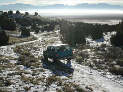 1994 Ford Bronco - A 1994 Ford Bronco navigates a snowy trail in a mountainous, arid landscape.