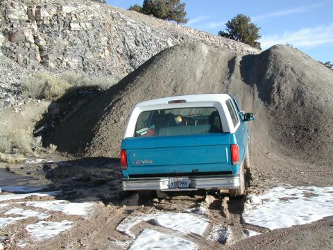 1994 Ford Bronco - A blue and white Ford Bronco navigates a challenging off-road course with mud and snow.
