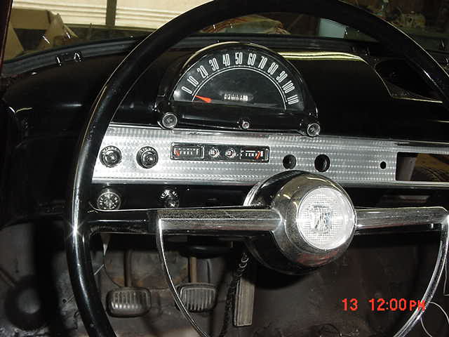 Vintage car instrument cluster with arc speedometer and chrome steering wheel hub