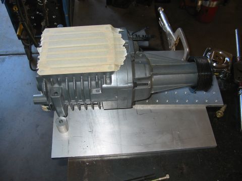 1993 Ford Taurus - A supercharger assembly is clamped to a metal plate, with masking tape covering the top portion.