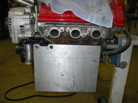 1993 Ford Taurus - Close-up view of an engine block and alternator, with a metal plate mounted to the side.
