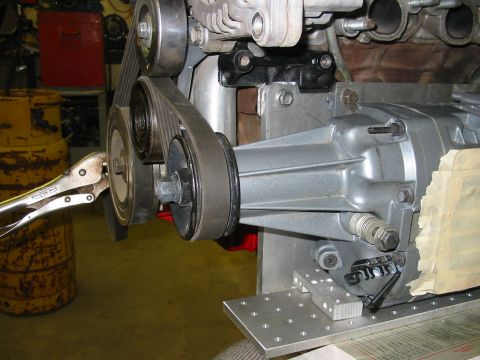 1993 Ford Taurus - A mechanic is working on an engine and transmission assembly, with a vise grip holding a pulley in place.
