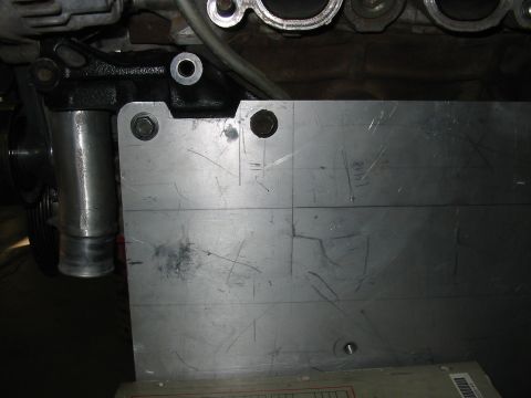 1993 Ford Taurus - A metal plate is bolted onto an engine component, showing some hand-drawn lines and markings.