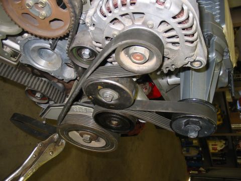 1993 Ford Taurus - The serpentine belt system of an engine is shown with various pulleys and the alternator.