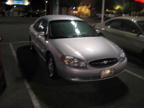 2002 Ford Taurus - A silver 2002 Ford Taurus is parked in a lot at night, with another vehicle visible to the right.