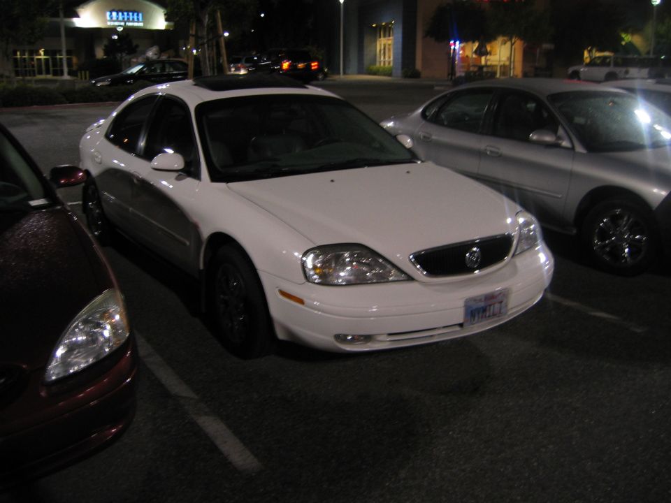 White sedan with a sunroof, front view. License plate reads NYK117
