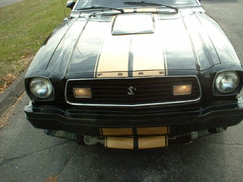1978 Ford Mustang II - The front grille of a 1978 Ford Mustang II features a prominent Cobra emblem and gold racing stripes.