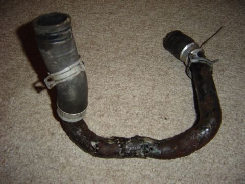 1998 Ford Taurus - This is a rusted metal pipe with rubber hoses and clamps, likely a coolant hose.