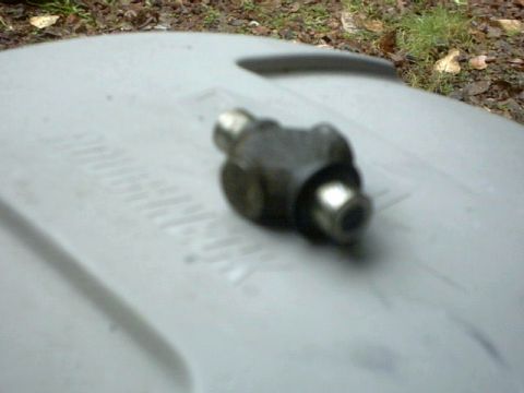 1995 Ford Bronco - A close-up of a metal automotive part is shown on a textured surface.