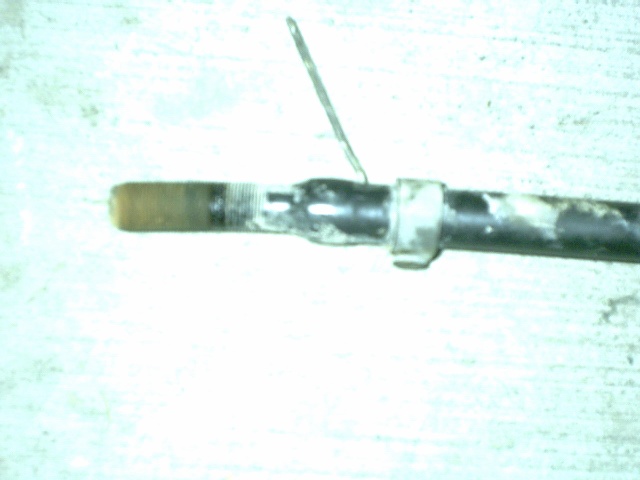 Close-up of a greasy threaded steel shaft end with a cotter pin through a cross-drilled hole