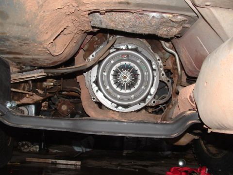 1990 Ford Bronco - Underside view of a vehicle showing an exposed clutch pressure plate and flywheel assembly bolted to the engine, with the transmission remo…
