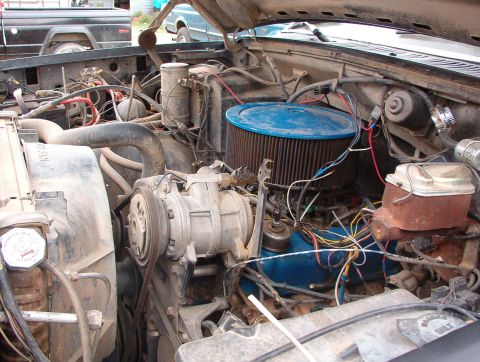 1985 Ford Bronco - The engine bay of a vehicle, a prominent blue air filter and a complex arrangement of hoses and wiring.