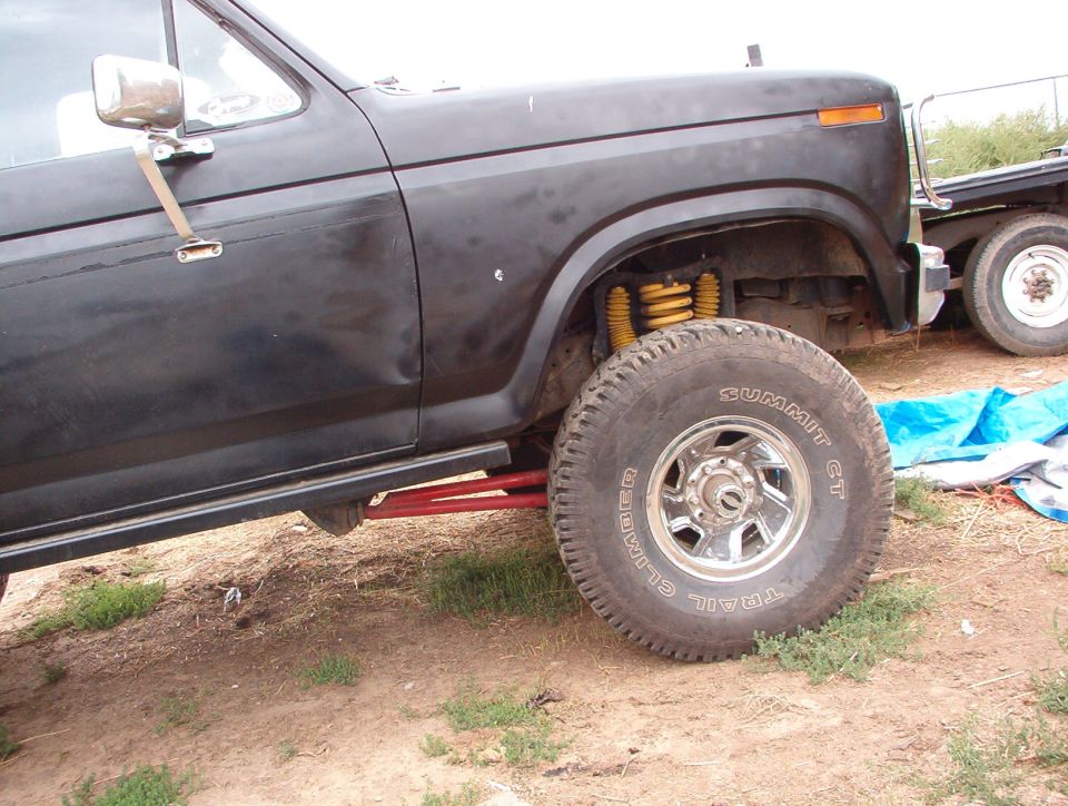 Black Ford truck, front wheel and fender area visible. Another vehicle is behind it