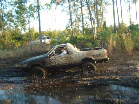 1993 Ford Bronco - A pickup truck navigates a muddy trail, with another vehicle visible in the background.
